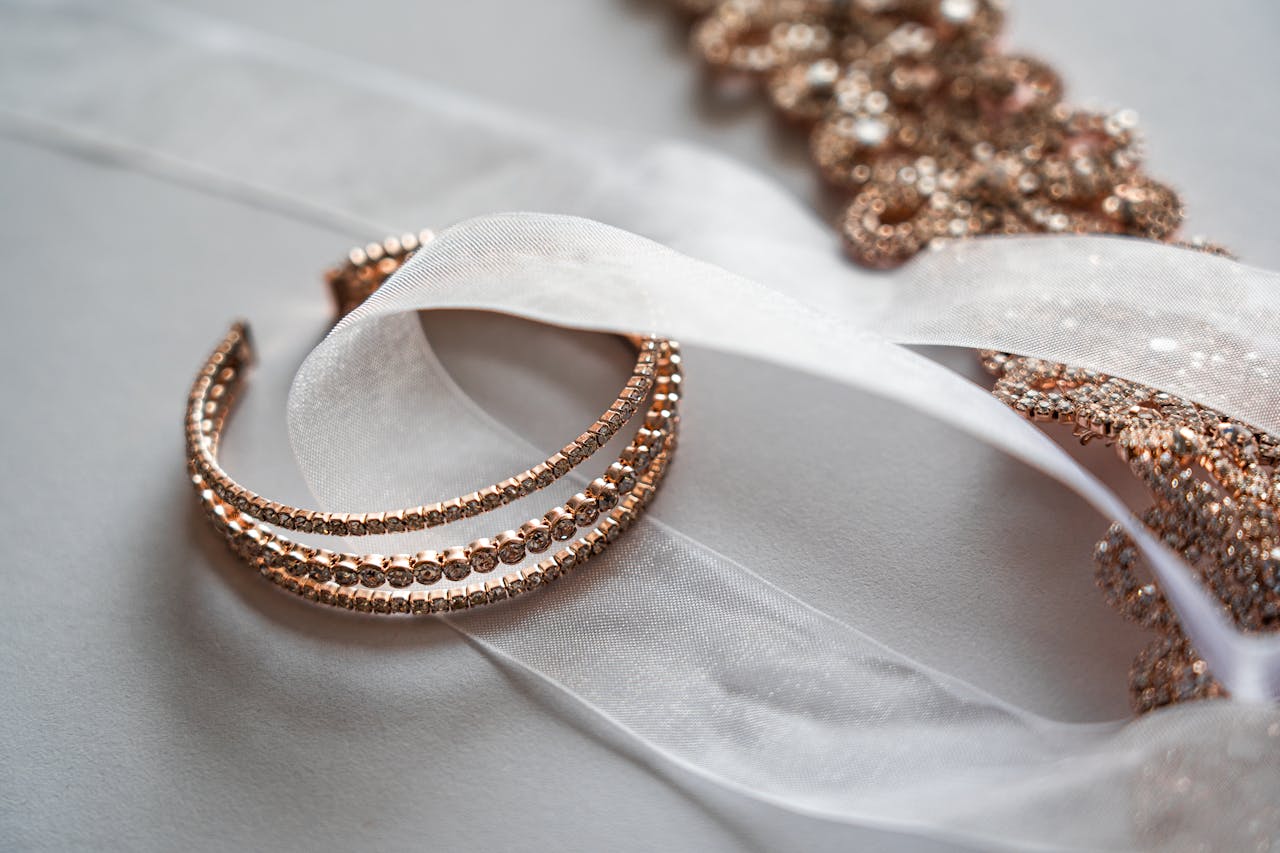 An elegant rose gold bracelet intertwined with sheer white ribbon.