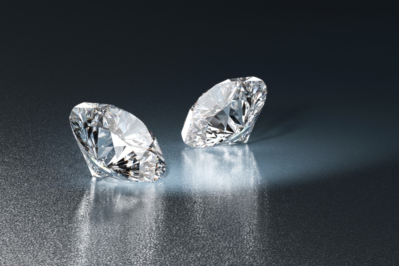 Two sparkling diamonds sitting on a reflective surface. Two sparkling diamonds sitting on a reflective surface.