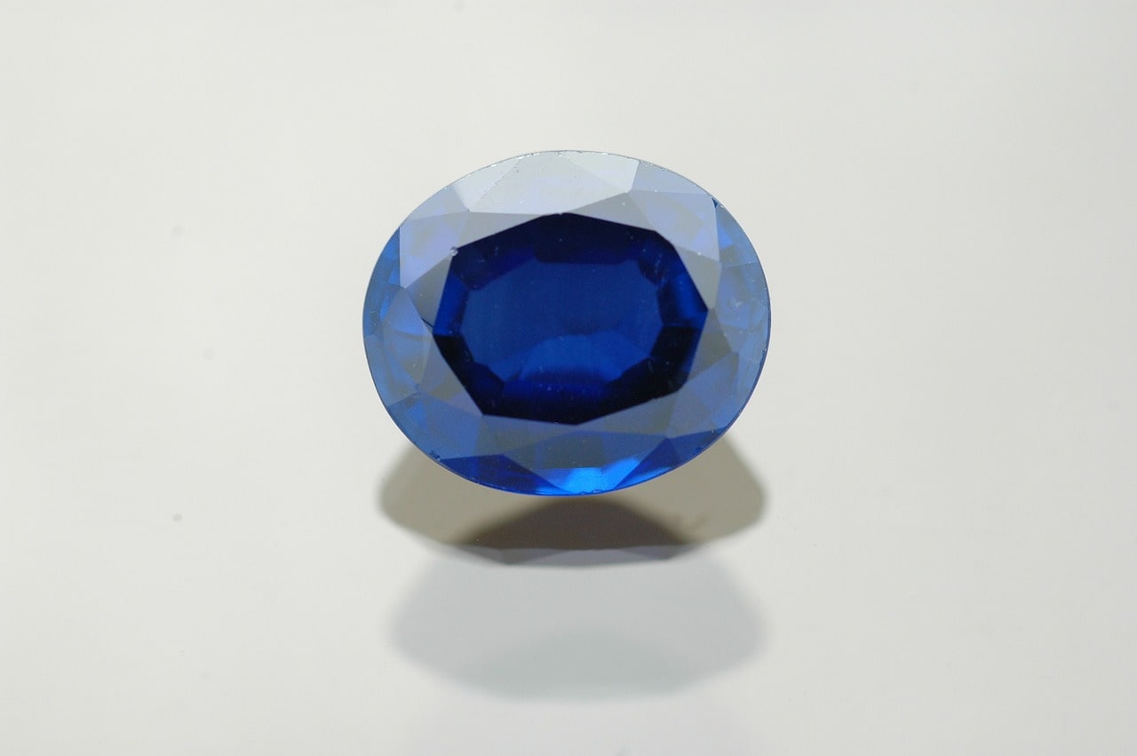 An oval deep blue sapphire on a white surface