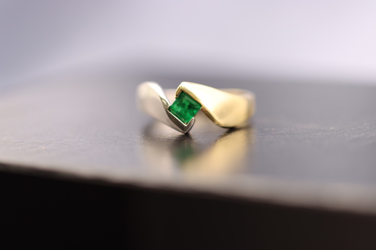 A yellow gold fashion ring with a princess cut emerald