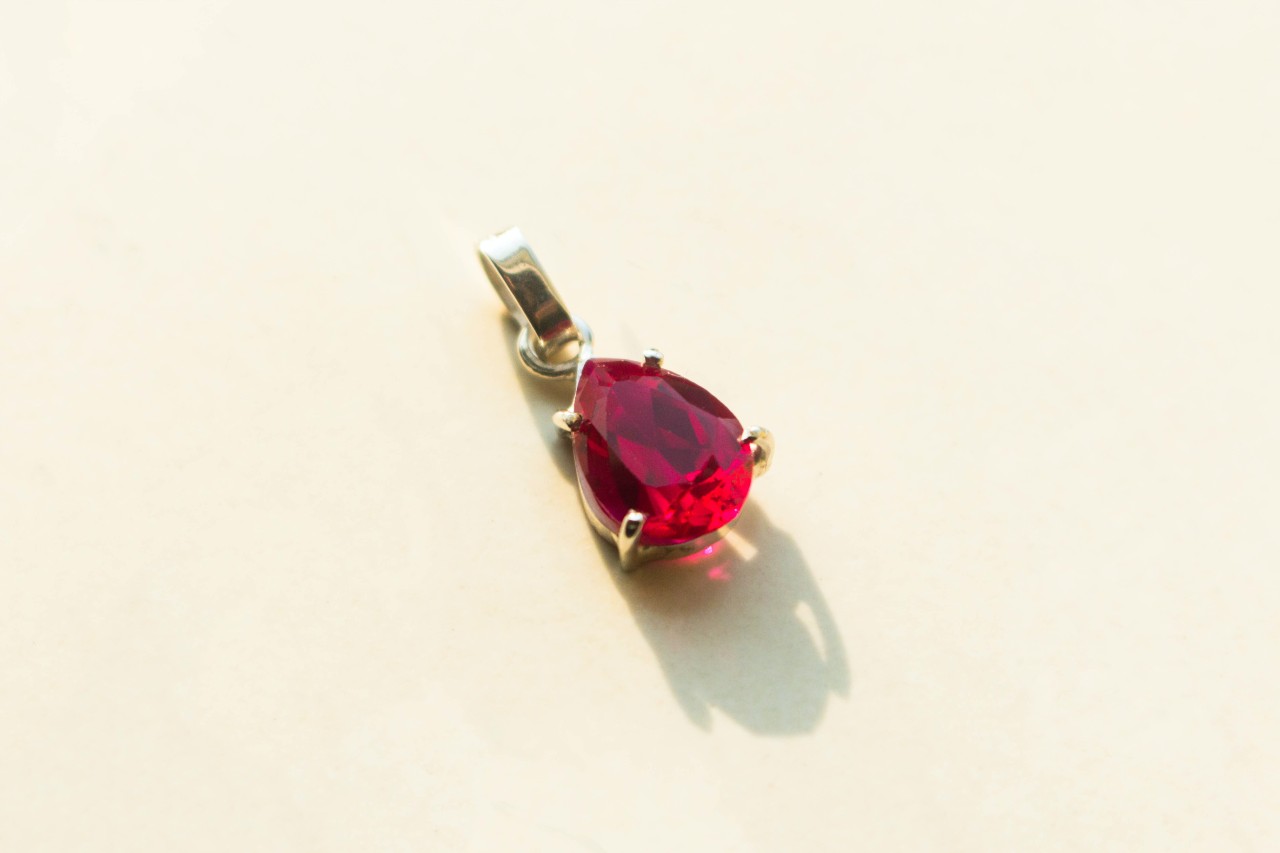 A yellow golf pear shaped ruby pendant on a white background