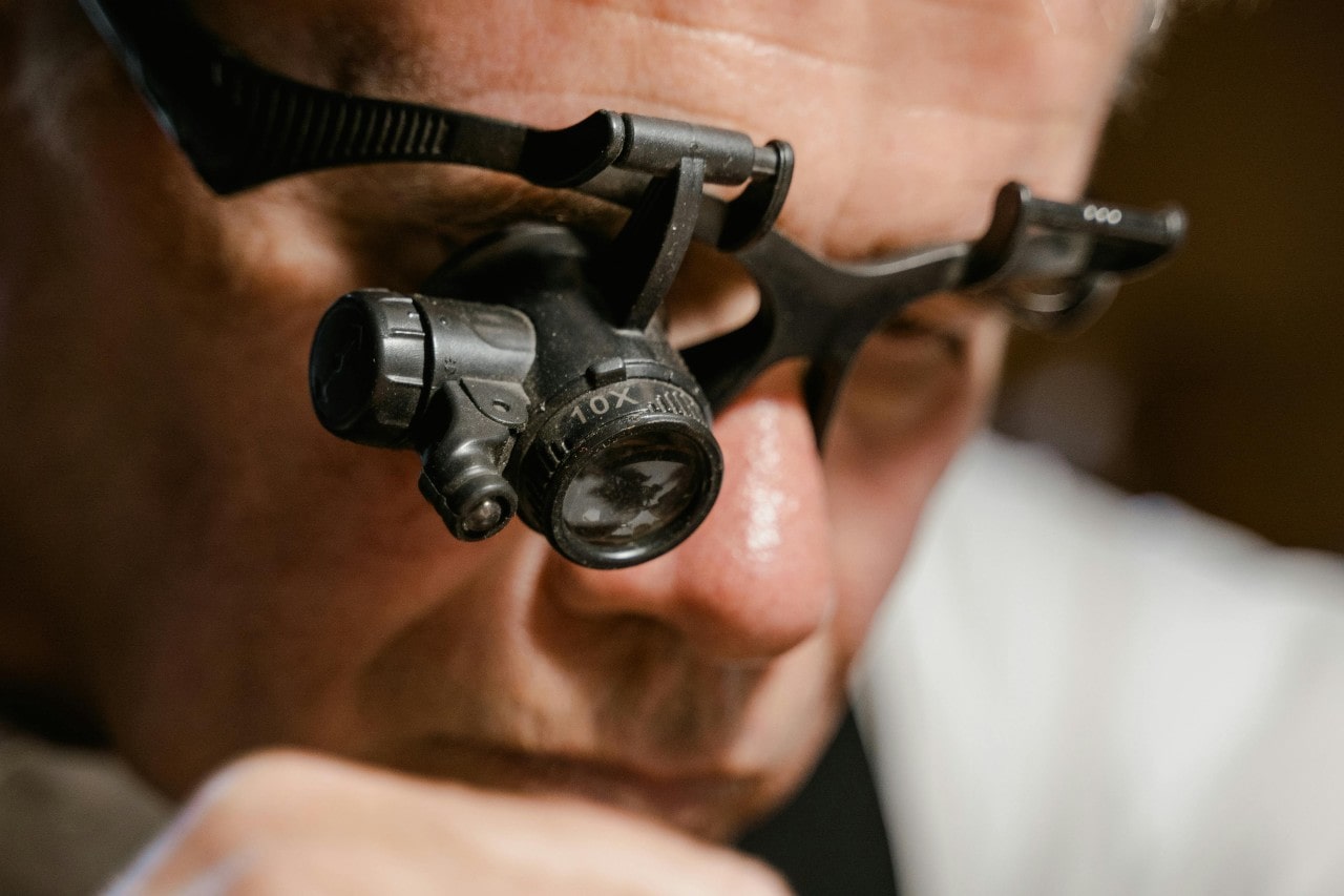 A close up of a jeweler wearing magnifying glasses.