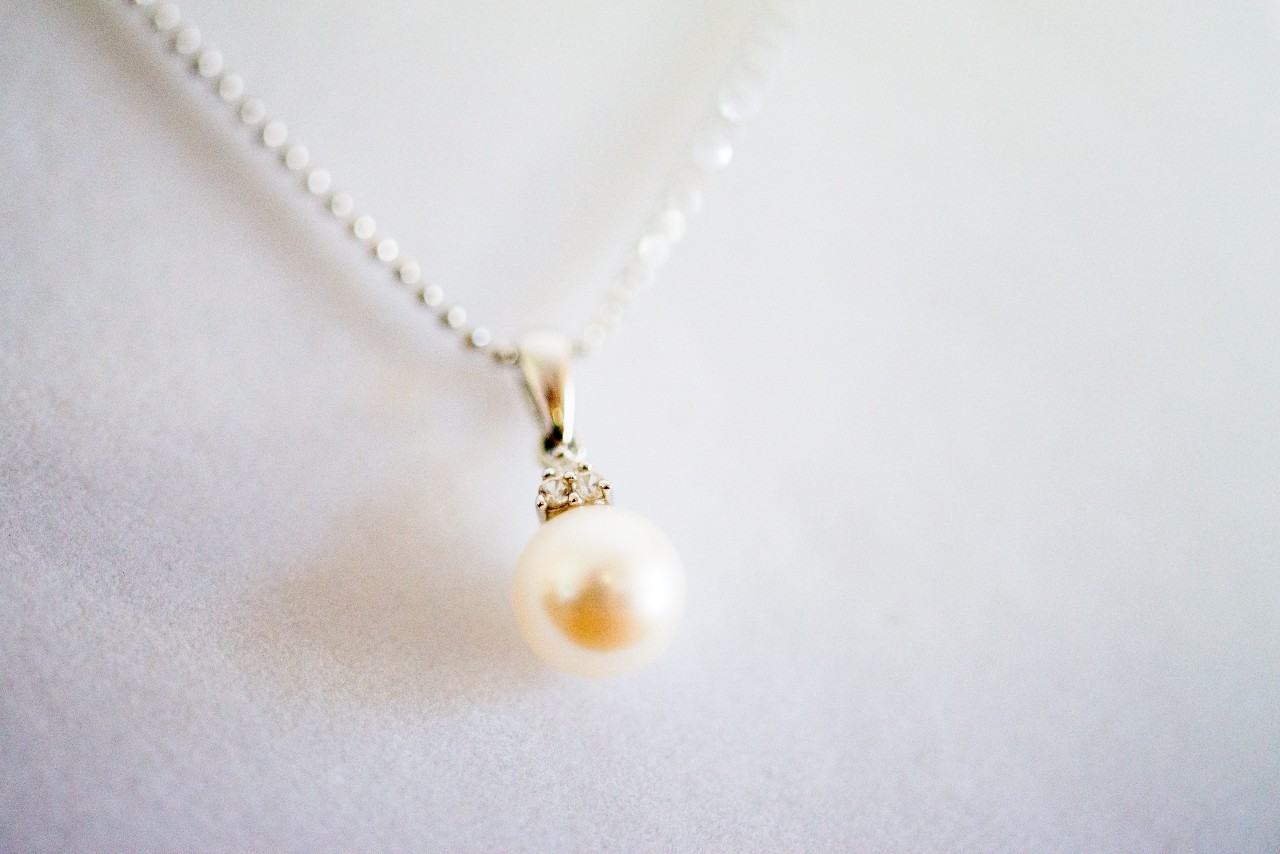 A pearl pendant necklace on a white surface.
